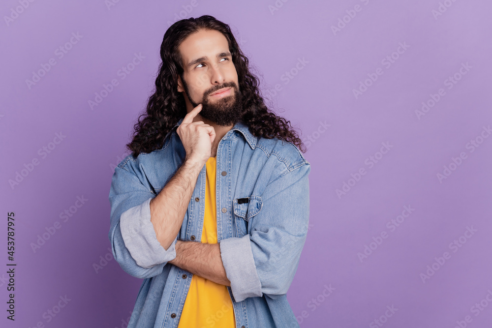 Portrait of handsome minded young man finger chin look up blank space on purple wall Portrait of handsome minded young man finger chin look up blank space on purple wall