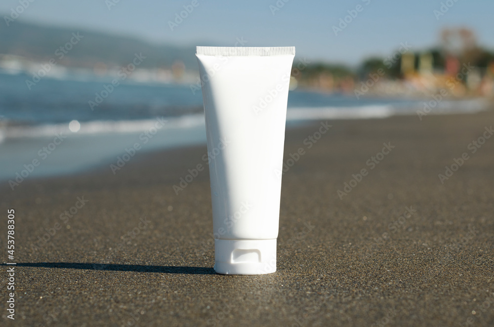 white clear cream tube mockup stands on wet sand on the background of the beach and the sea, sunscreen lotion concept