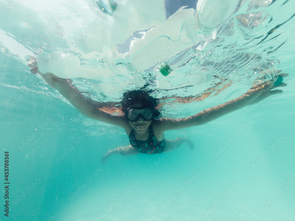 Girl swimming in a swimming pool with plastic bottles 