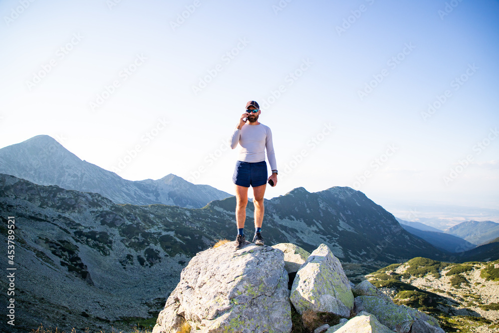 man using mobile phone on mountain top