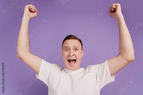 Portrait of positive crazy screaming man raise fists open mouth on violet background
