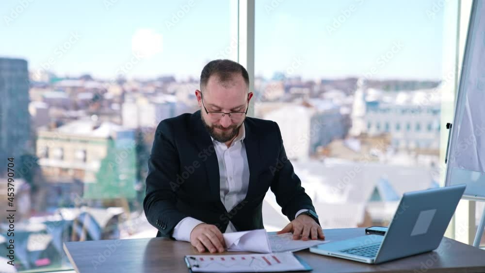 Depressed businessman sitting at desk. Bearded middle aged man in glasses feeling nervous at his workplace. Portrait of sad businessman in office Depressed businessman sitting at desk. Bearded middle aged man in glasses feeling nervous at his workplace. Portrait of sad businessman in office