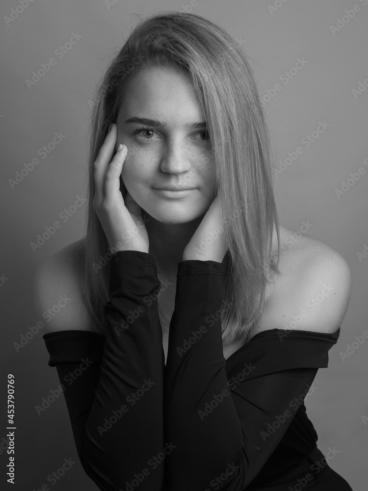 Girl, blonde, shoulder-length hair. Posing in the studio on a light background. Black clothes. Spring summer type. Baby face. Black and white photo Girl, blonde, shoulder-length hair. Posing in the studio on a light background. Black clothes. Spring summer type. Baby face. Black and white photo