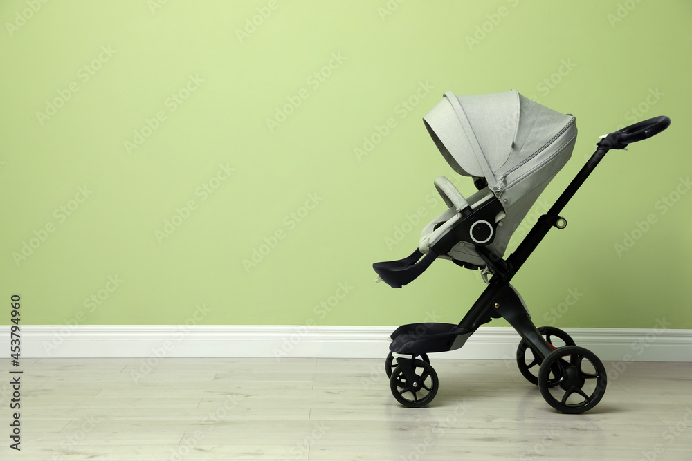 Baby carriage. Modern pram near light green wall, space for text Baby carriage. Modern pram near light green wall, space for text