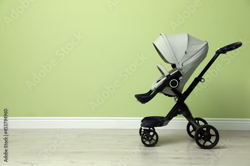 Baby carriage. Modern pram near light green wall, space for text photo