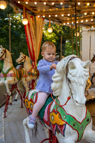 Cute baby girl on the horse of old retro carousel, Prague, Czech republic 