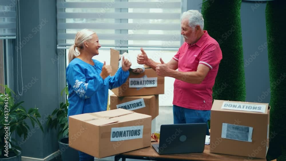 Senior couple at the donation center give high five at the successful packaging of goods Senior couple at the donation center give high five at the successful packaging of goods