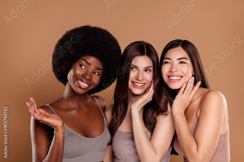 Photo of dreamy fancy three best friends wear cropped tops smiling hugging looking empty space isolated beige color background © Beauty Hero