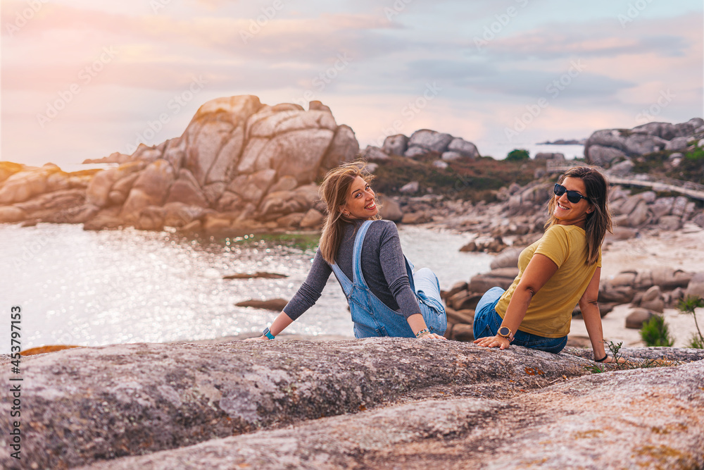 Two female friends sitting on a rock Two female friends sitting on a rock