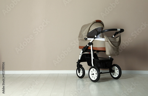 Baby carriage. Modern pram near beige wall, space for text photo