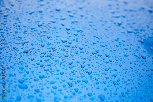 Vibrant blue metal surface covered in water drops, selective focus.