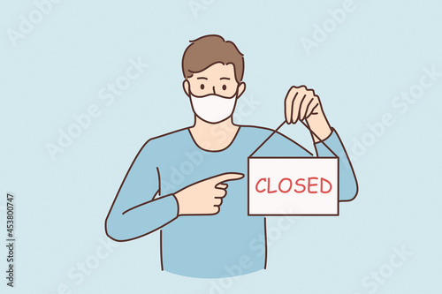 Business crisis during pandemic concept. Young sad man in protective medical mask standing showing sign with closed word during covid epidemic concept vector illustration 