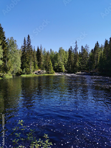 A picturesque waterfall on the Tokhmayoki River in Karelia surrounded by trees on a clear summer morning. photo