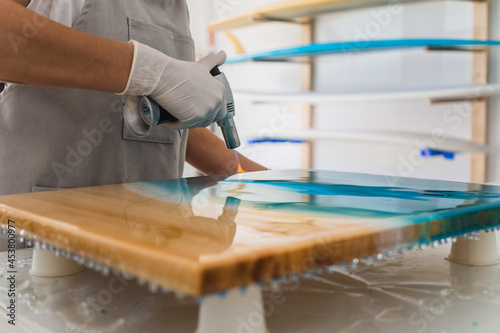Female artist drying resin paint with a blowtorch