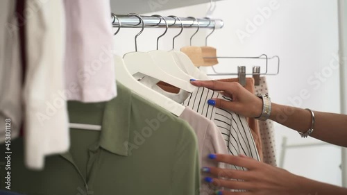 Wardrobe with clothes collection. Spbd Hands of black lady choose elegant apparels hanging on rack metal bar in light dressing room at home closeup photo