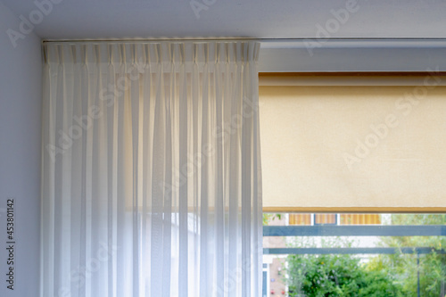 Light and see through concept, Classic white sheer curtains hanging by the window in the room with blurred outside view as background.