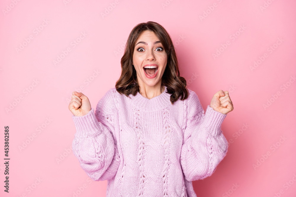 Photo of adorable lucky young lady wear knitted pullover rising fists open mouth isolated pastel pink color background Photo of adorable lucky young lady wear knitted pullover rising fists open mouth isolated pastel pink color background
