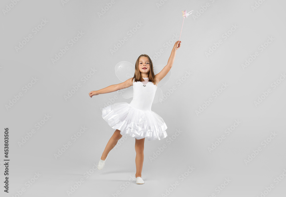Cute little girl in fairy costume with wings and magic wand on light background. Space for text Cute little girl in fairy costume with wings and magic wand on light background. Space for text