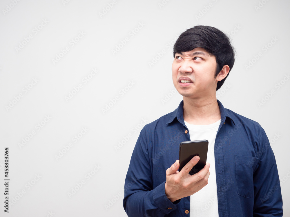 Man holding mobile phone feeling angry looking at copy space white isolated background Man holding mobile phone feeling angry looking at copy space white isolated background