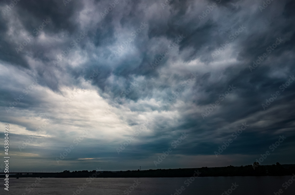 Dramatic beautiful stormy sky over the lake. Large gray rain and motley cloud above the horizon