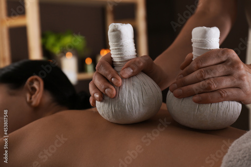 Young woman receiving herbal bag massage in spa salon, closeup