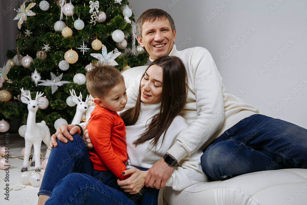 family posing against the background of the christmas tree family posing against the background of the christmas tree