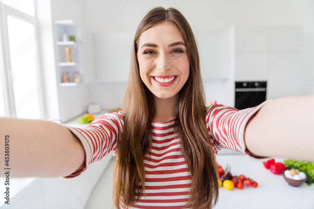 Photo of happy positive young woman make selfie hold hands camera smile good mood indoors inside kitchen Photo of happy positive young woman make selfie hold hands camera smile good mood indoors inside kitchen