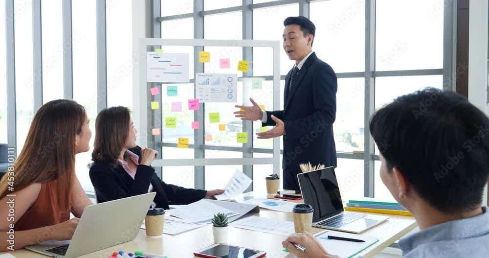 Group of business people meeting in conference room. Asian businessman speech, present teamwork partnership. Happy business people meeting present graph chart investment, business data in meeting room