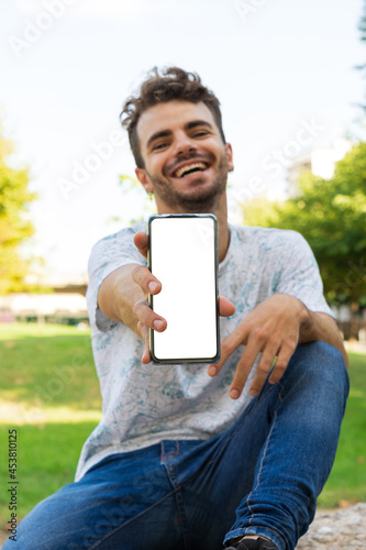 Caucasian man in park with cellphone in hand smiling photo