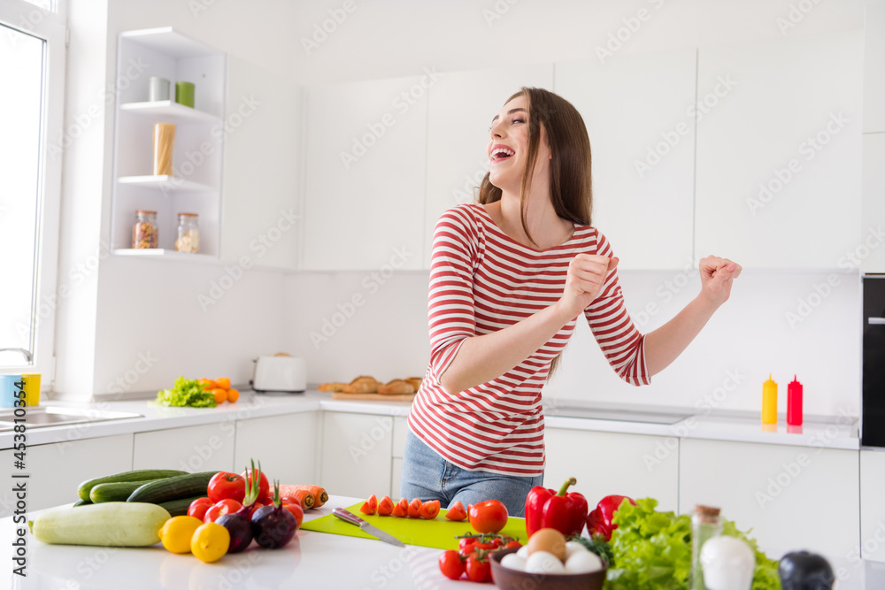 Portrait of attractive carefree cheerful girl dancing cooking useful tasty dish good mood at home light white kitchen indoors