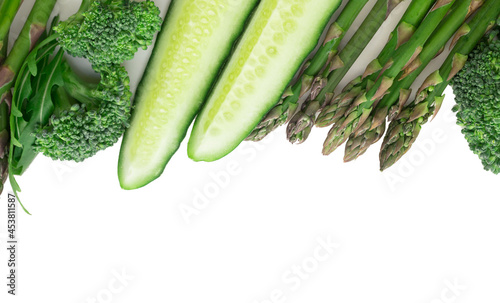 frame of green vegetables broccoli, arugula, cucumber, asparagus and garlic on white background