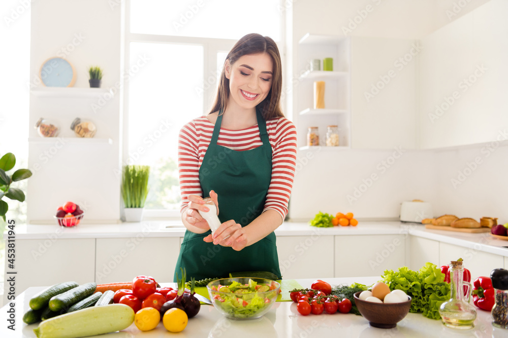 Photo of pretty happy positive young woman hold salt make salad health food wear apron indoors inside kitchen