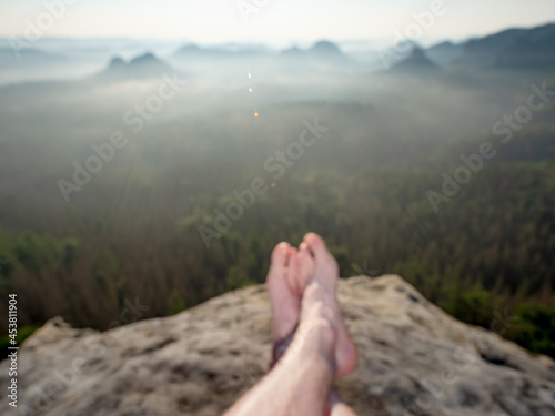 Short break on the mountain trek. Man sit or lay down on the cliff edge