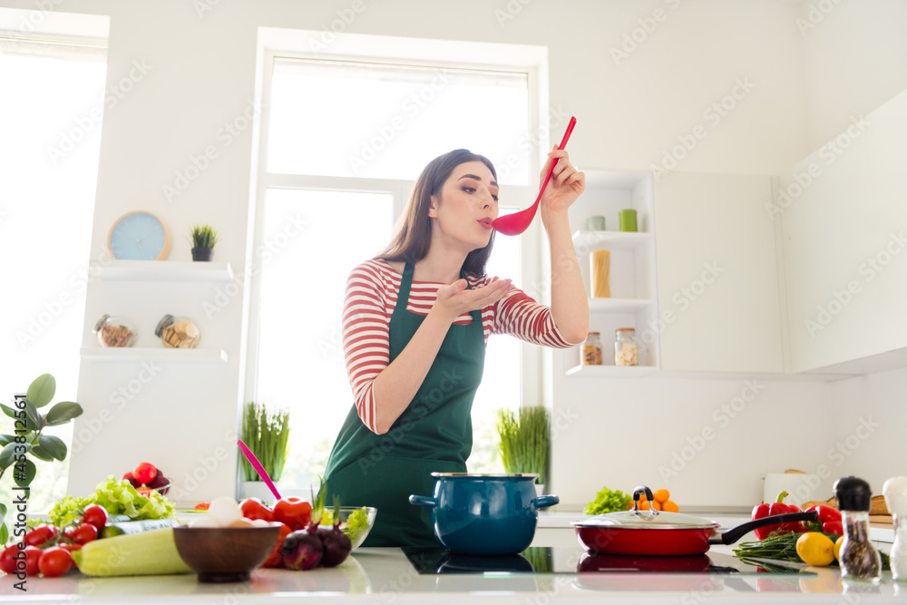 Photo of dreamy charming house wife wear green trying tasty dinner indoors room home house
