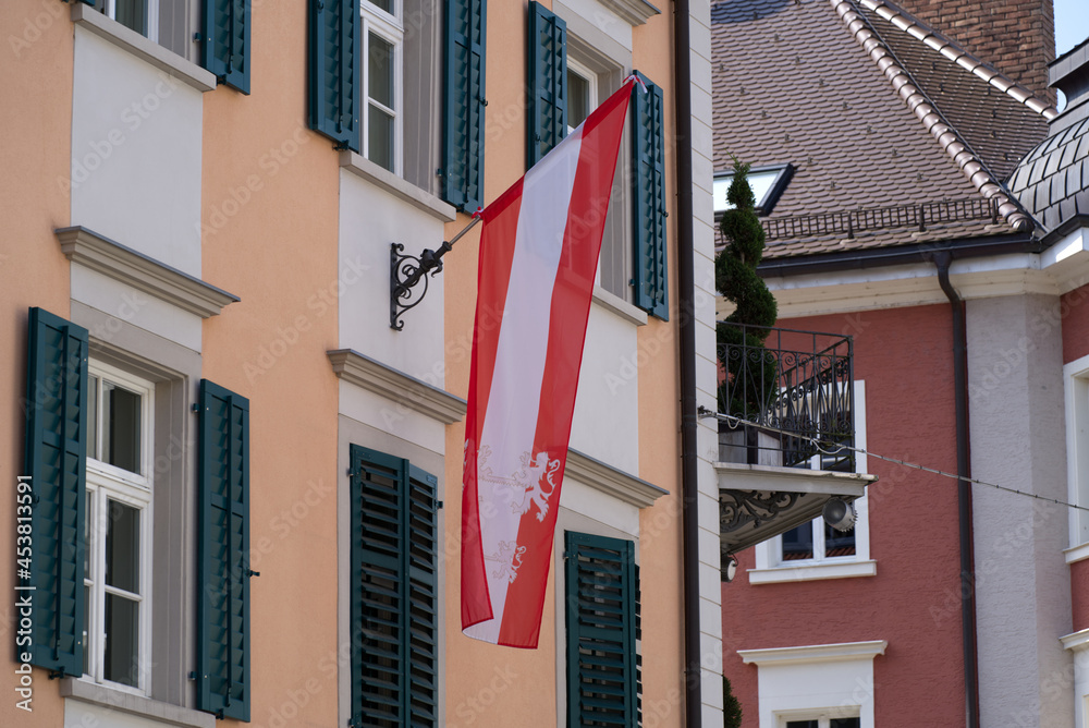 Austrian flag blowing in the wind at the old town of Bregenz on a sunny summer Sunday. Photo taken August 15th, 2021, Bregenz, Austria. Austrian flag blowing in the wind at the old town of Bregenz on a sunny summer Sunday. Photo taken August 15th, 2021, Bregenz, Austria.