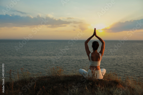 Woman meditating near sea, back view. Space for text © New Africa