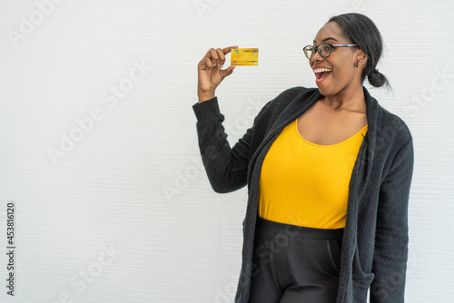 South African black woman holds a credit card, has the power to spend money, and has the credit to make a happy online purchase. 