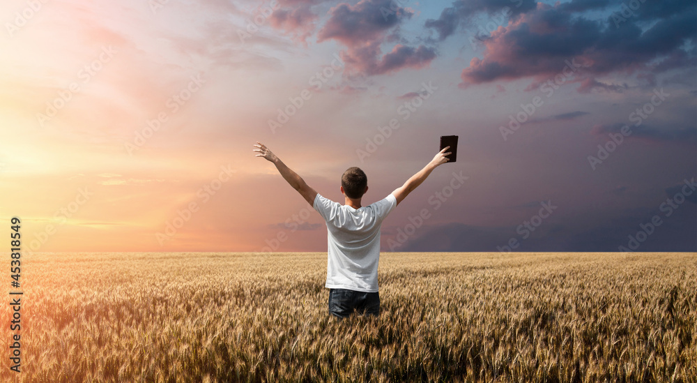 man holding up Bible in a wheat field man holding up Bible in a wheat field