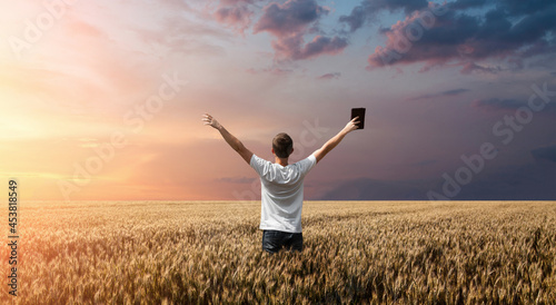 Fotografie, Obraz man holding up Bible in a wheat field