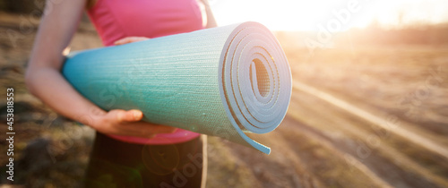 Foto woman walking with a yoga mat outside during sunset n a rural area wearing sport
