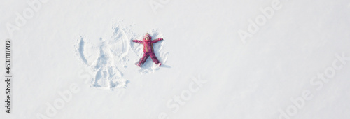Child girl playing and making a snow angel in the snow. Top flat overhead view photo