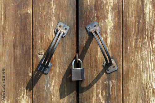 Two handles and padlock on a closed wooden door
