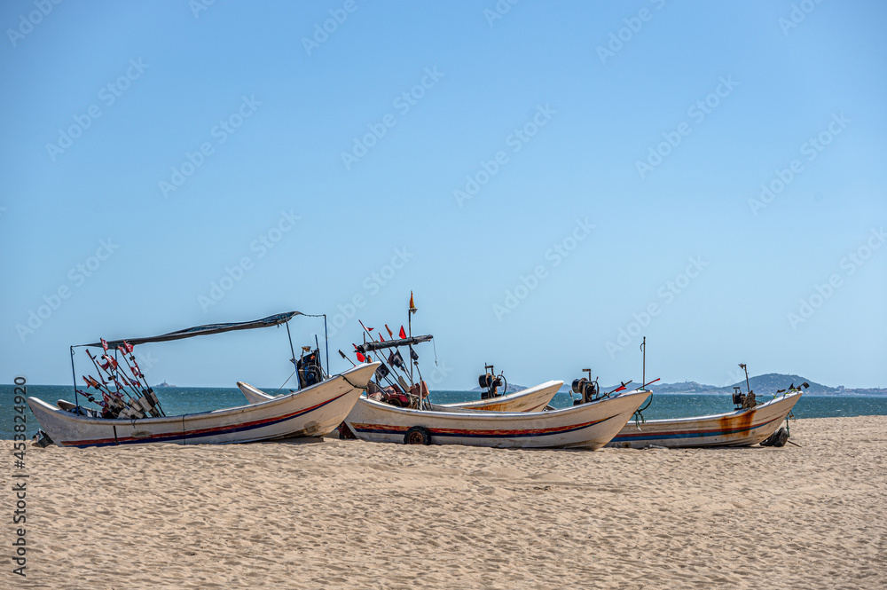 Some boats docked on the beach, blue sky, sea and beach