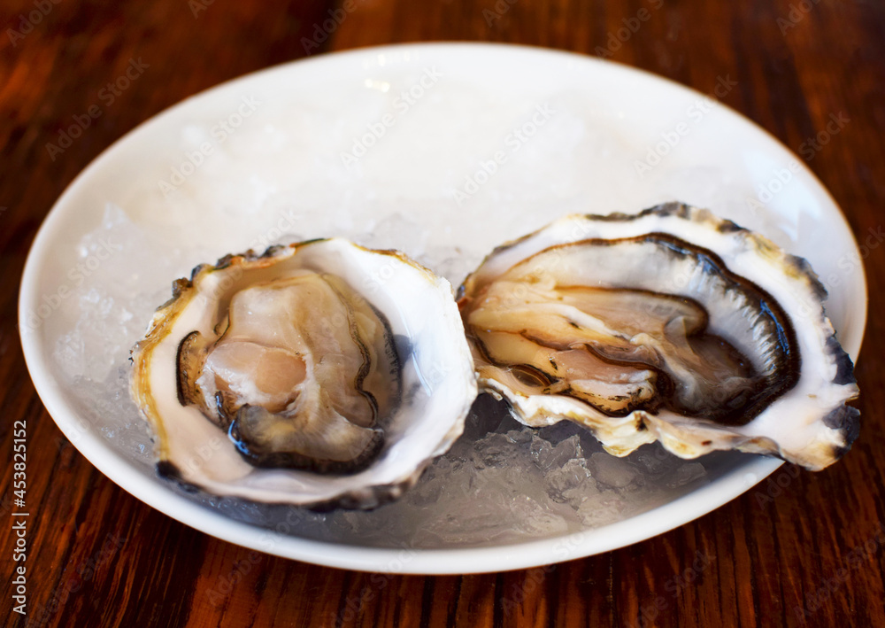 Two fresh, open oysters lie on a plate of ice. Sea food, aphrodisiac