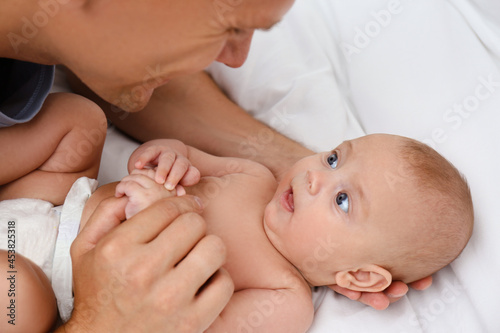 Happy father with his cute baby on bed, closeup
