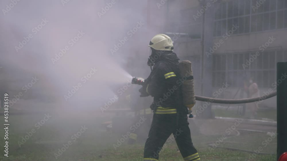 Firefighters pouring water from hoses on lawn Firefighters pouring water from hoses on lawn
