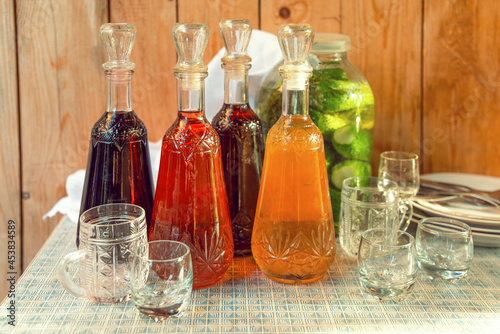 Various wines in decanters, a jar of cucumbers and glass mugs on the table.