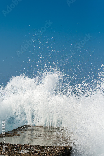sea wave crashes on a concrete pier,  vertical view