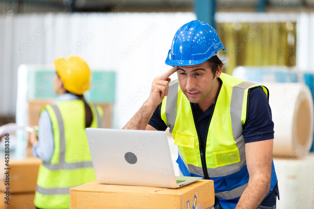 engineer or factory worker using laptop computer and thinking of something seriously in warehouse storage engineer or factory worker using laptop computer and thinking of something seriously in warehouse storage