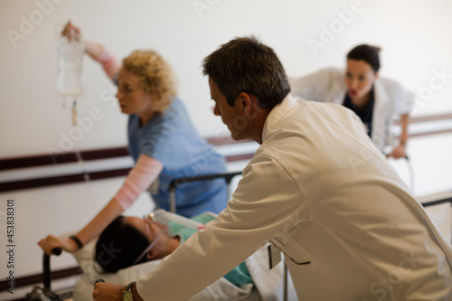 Doctors rushing patient on gurney in hospital corridor